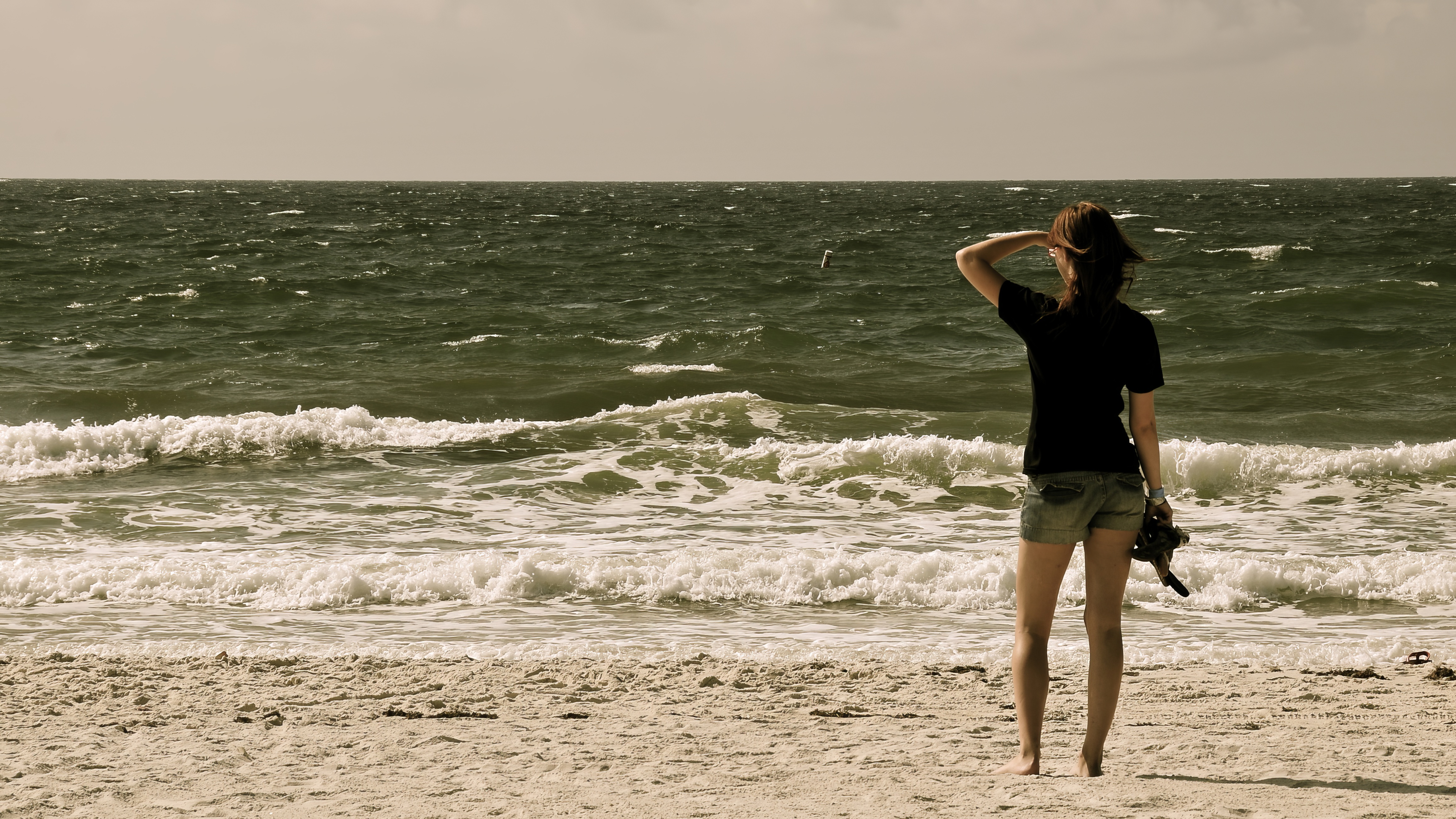 a woman standing on a beach with a kite in her hand