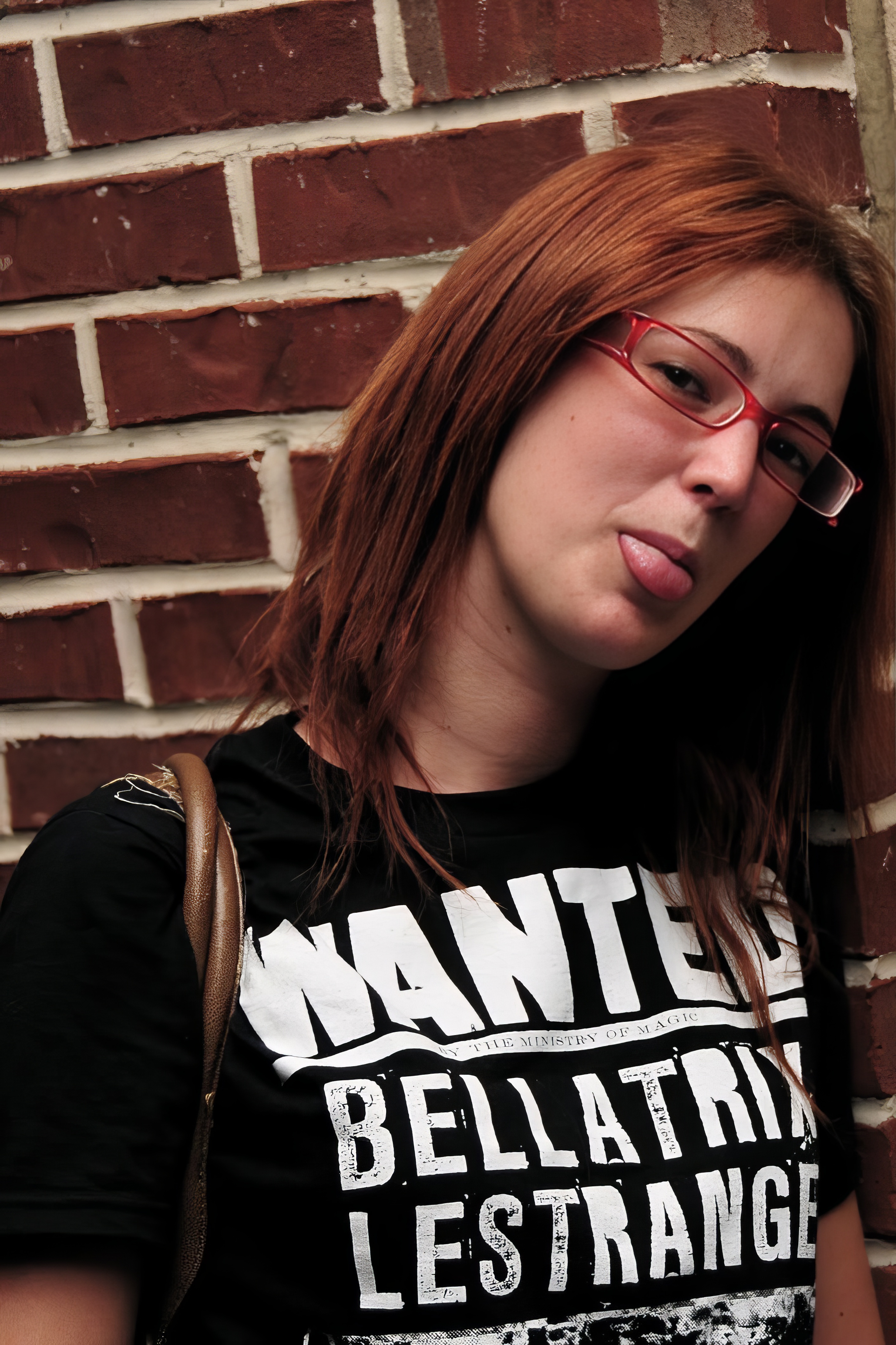 a woman with red hair and glasses is leaning against a brick wall