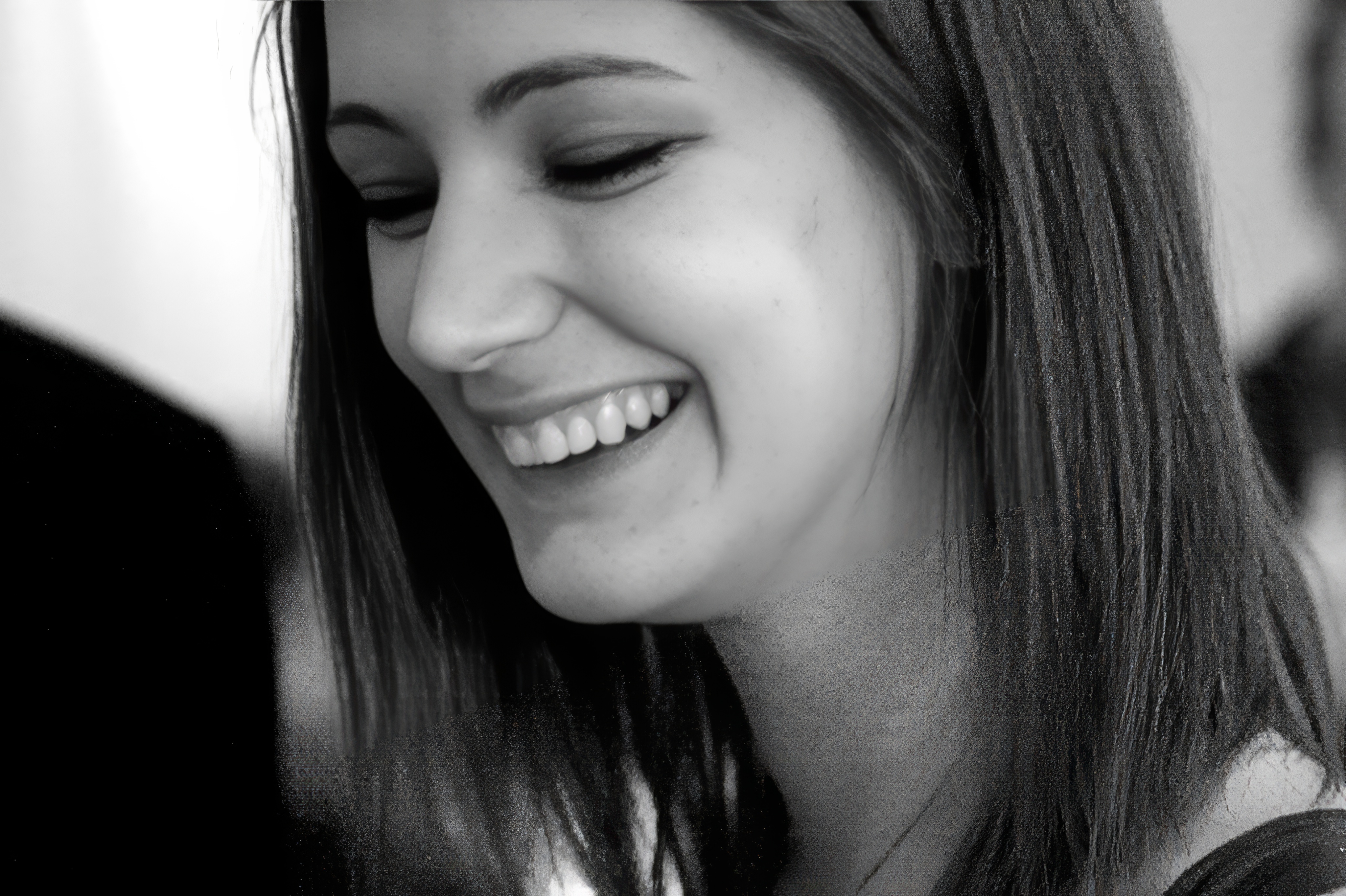 a woman smiling while she looks at her cellphone an ‘