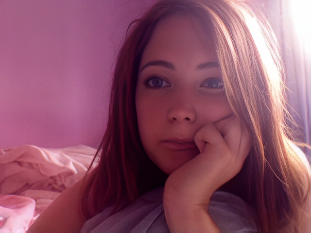 a woman laying on a bed with her hand on her chin