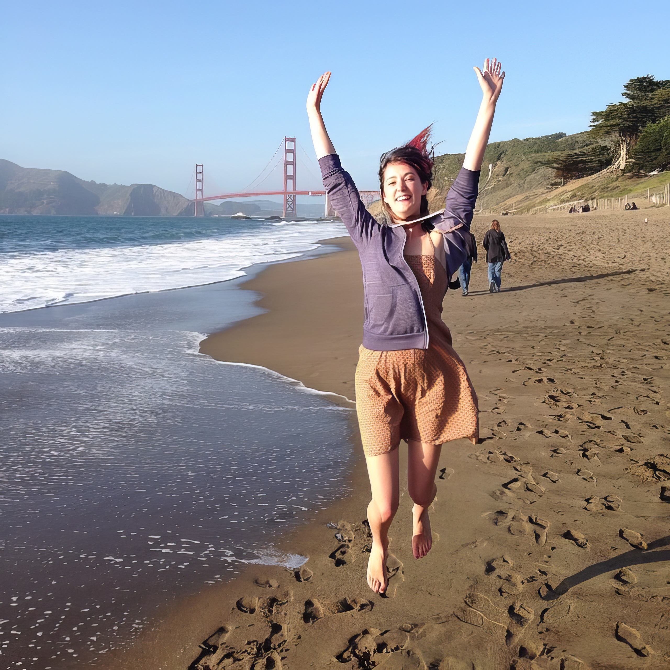 a woman is running on the beach with her arms up