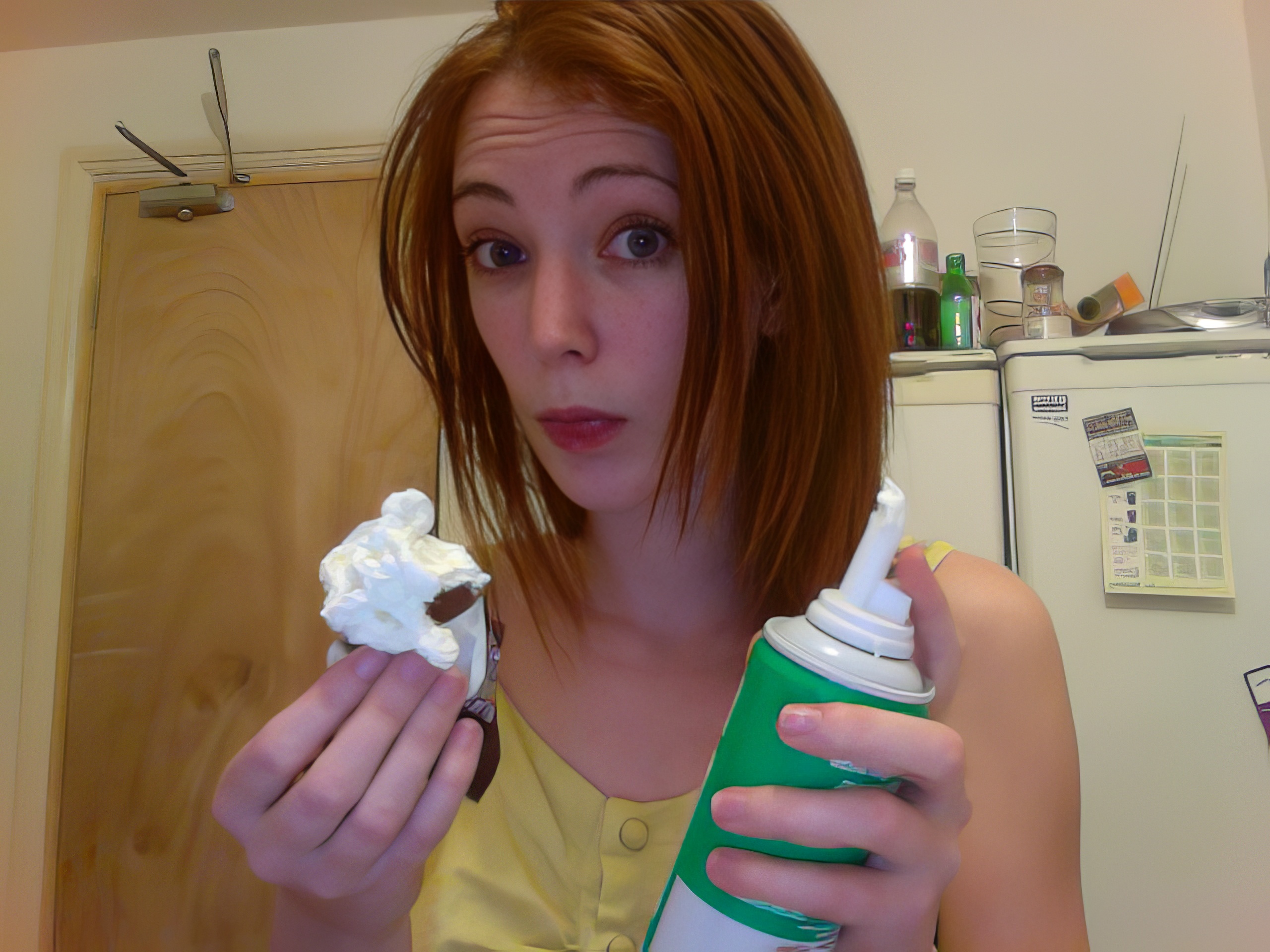 a woman holding a cup and a bottle of whipped cream