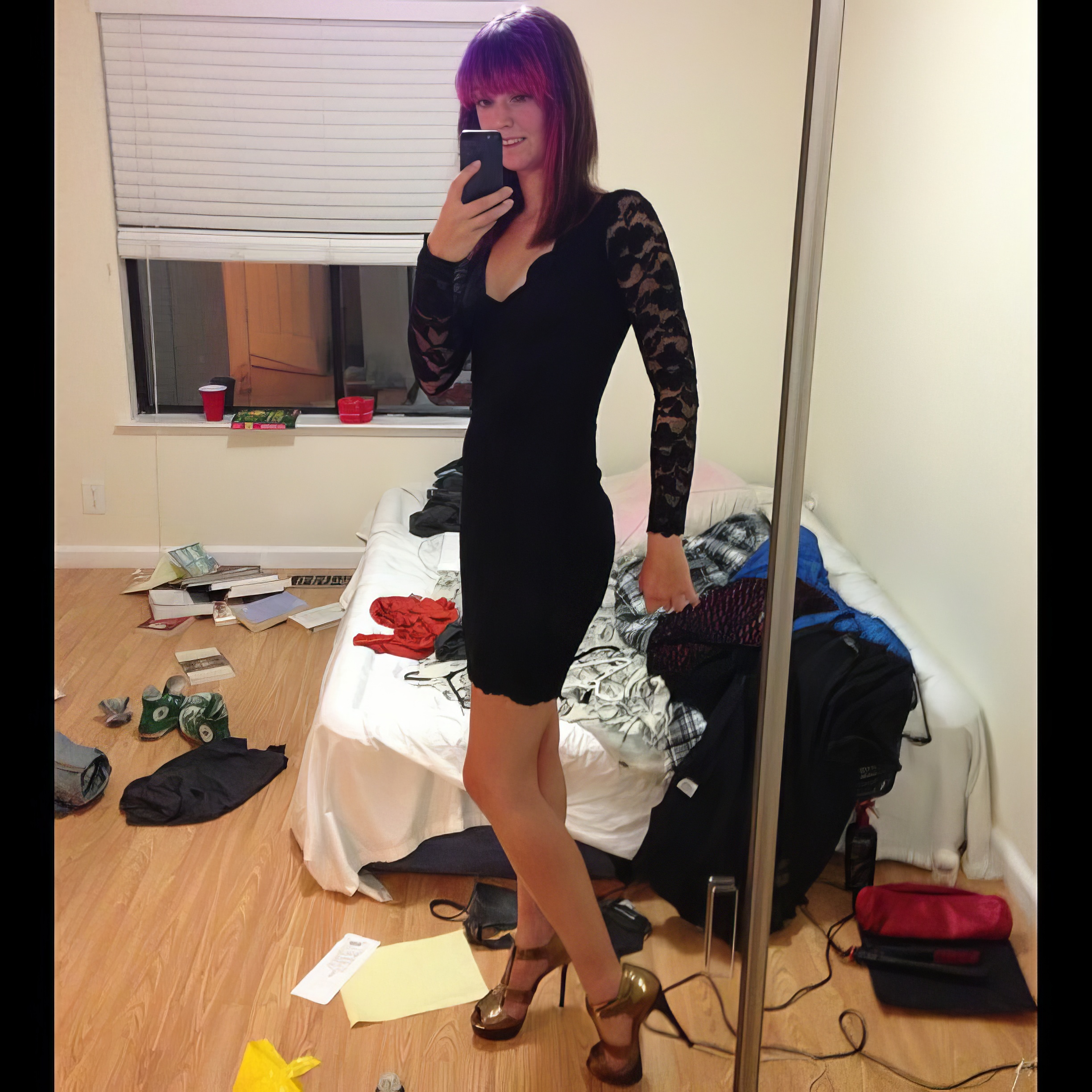 a woman in a black dress is standing in front of a mirror