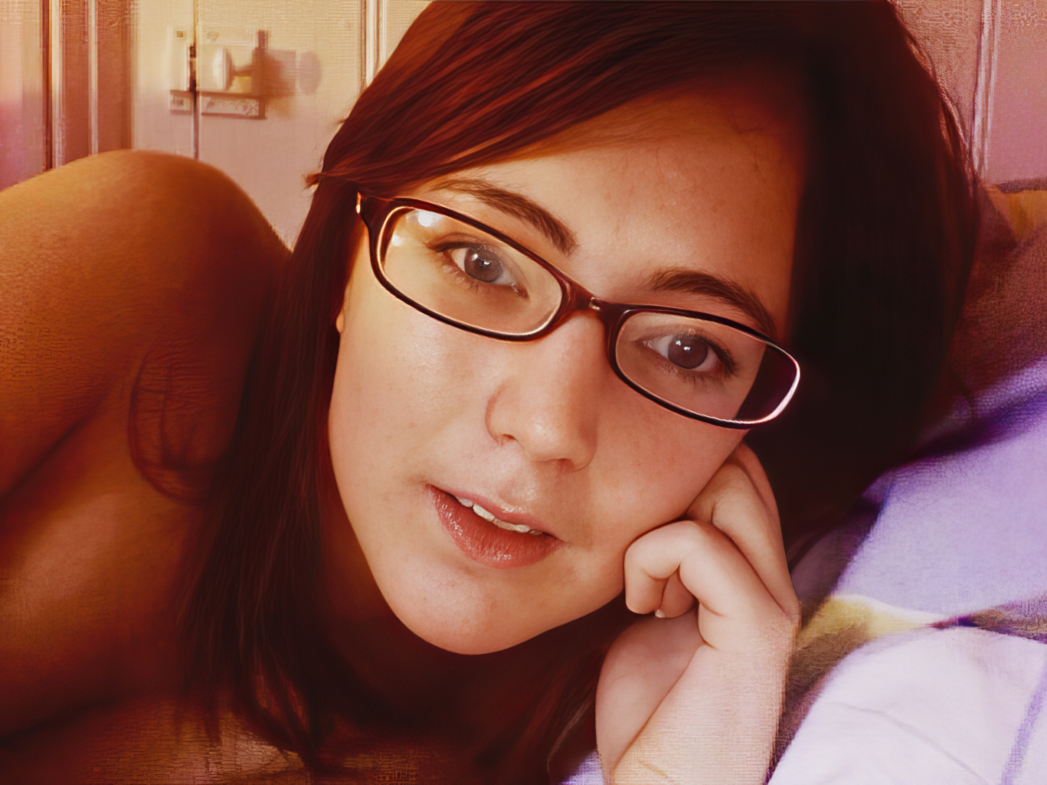 a woman with glasses laying on a bed