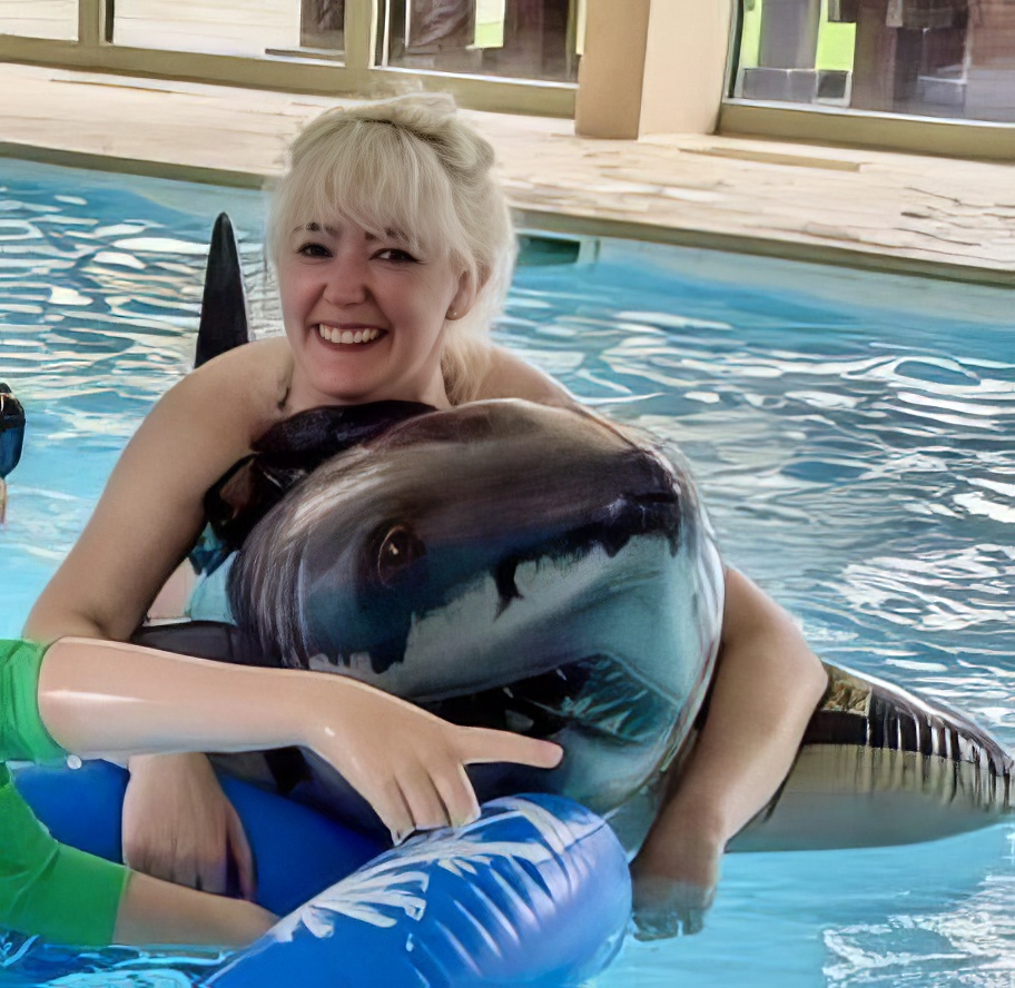 a woman in a pool with a dolphin