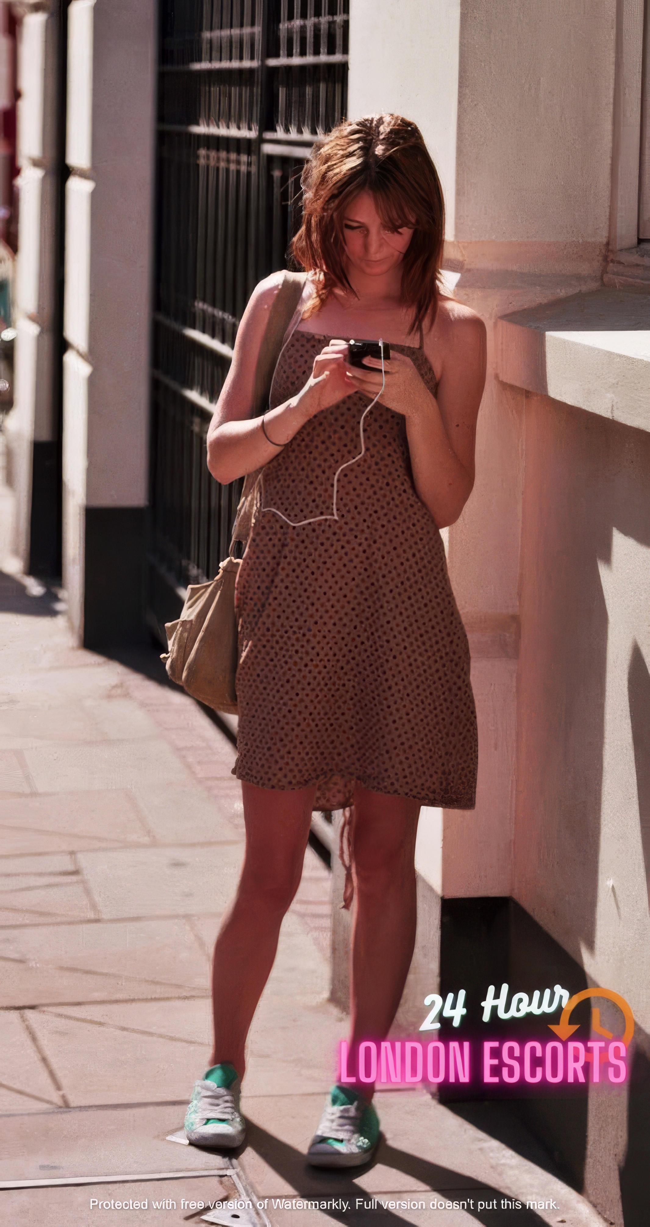 a woman standing on a sidewalk while looking at her cellphone