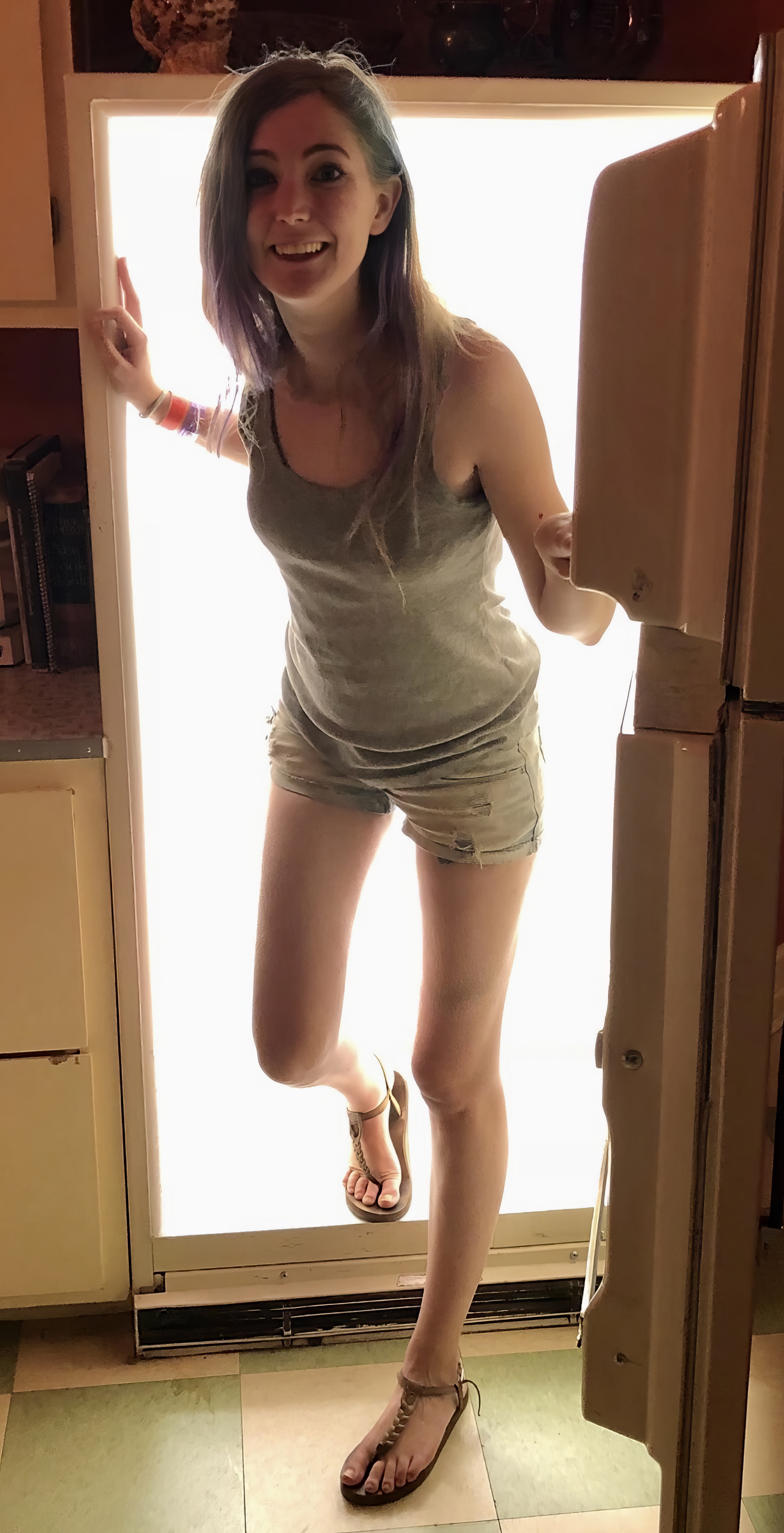 a woman in a gray shirt and shorts is standing in a doorway