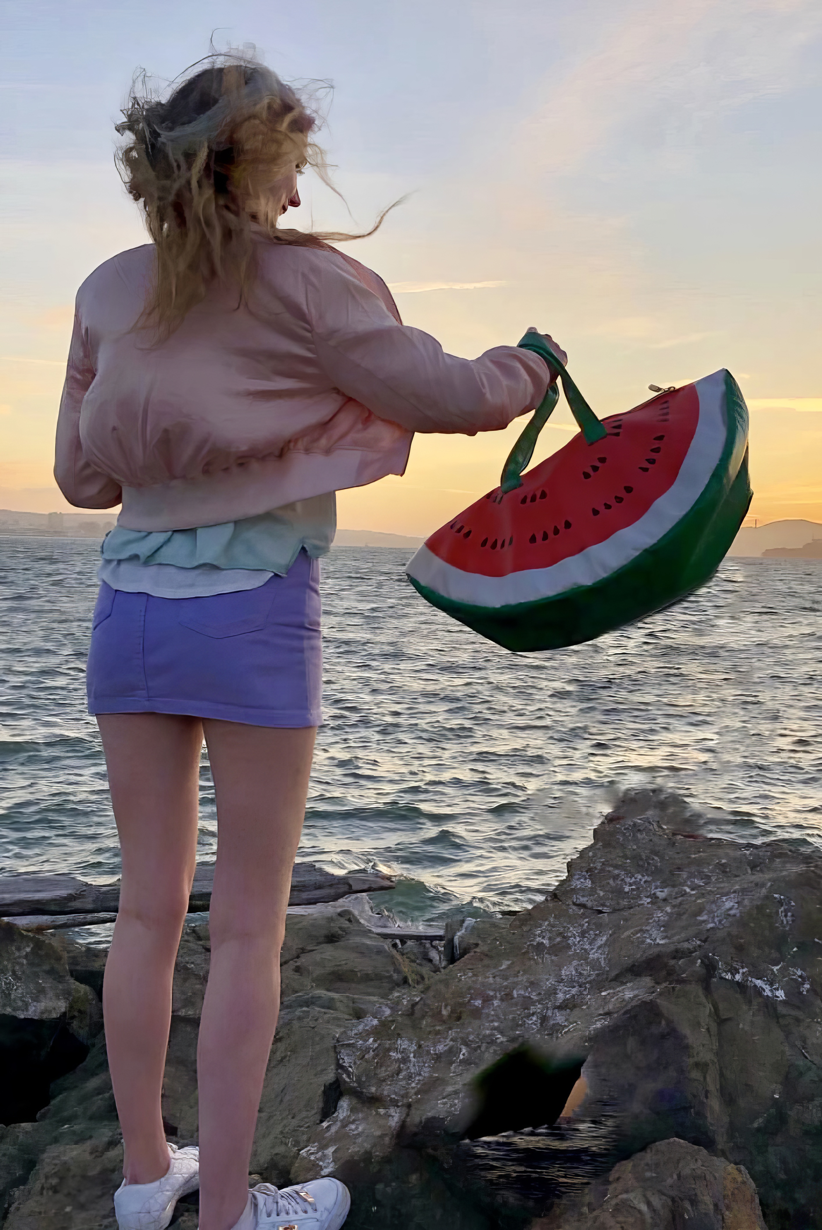 a woman standing on a rock with a watermelon