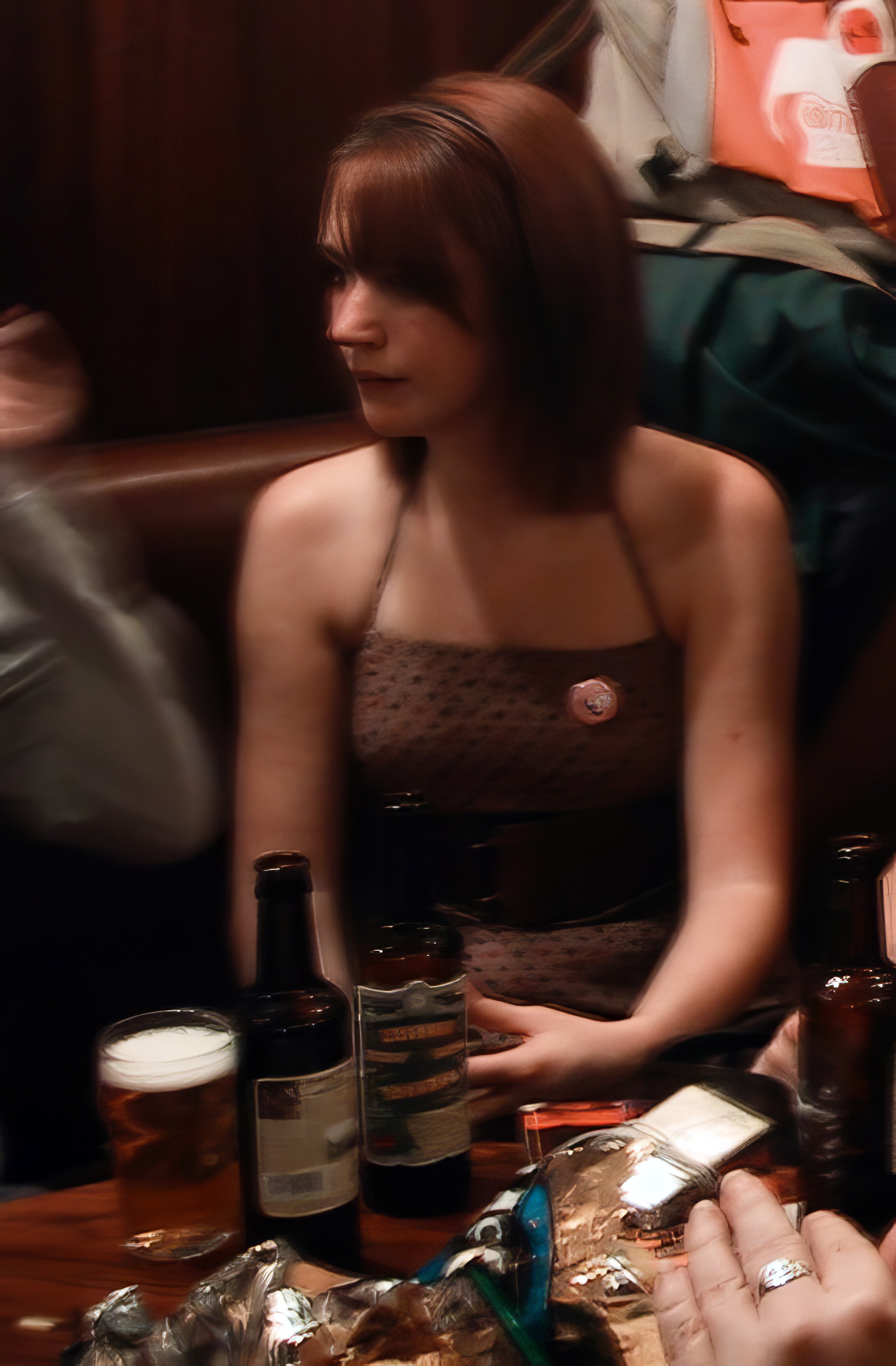 a woman sitting at a table with a bottle of beer