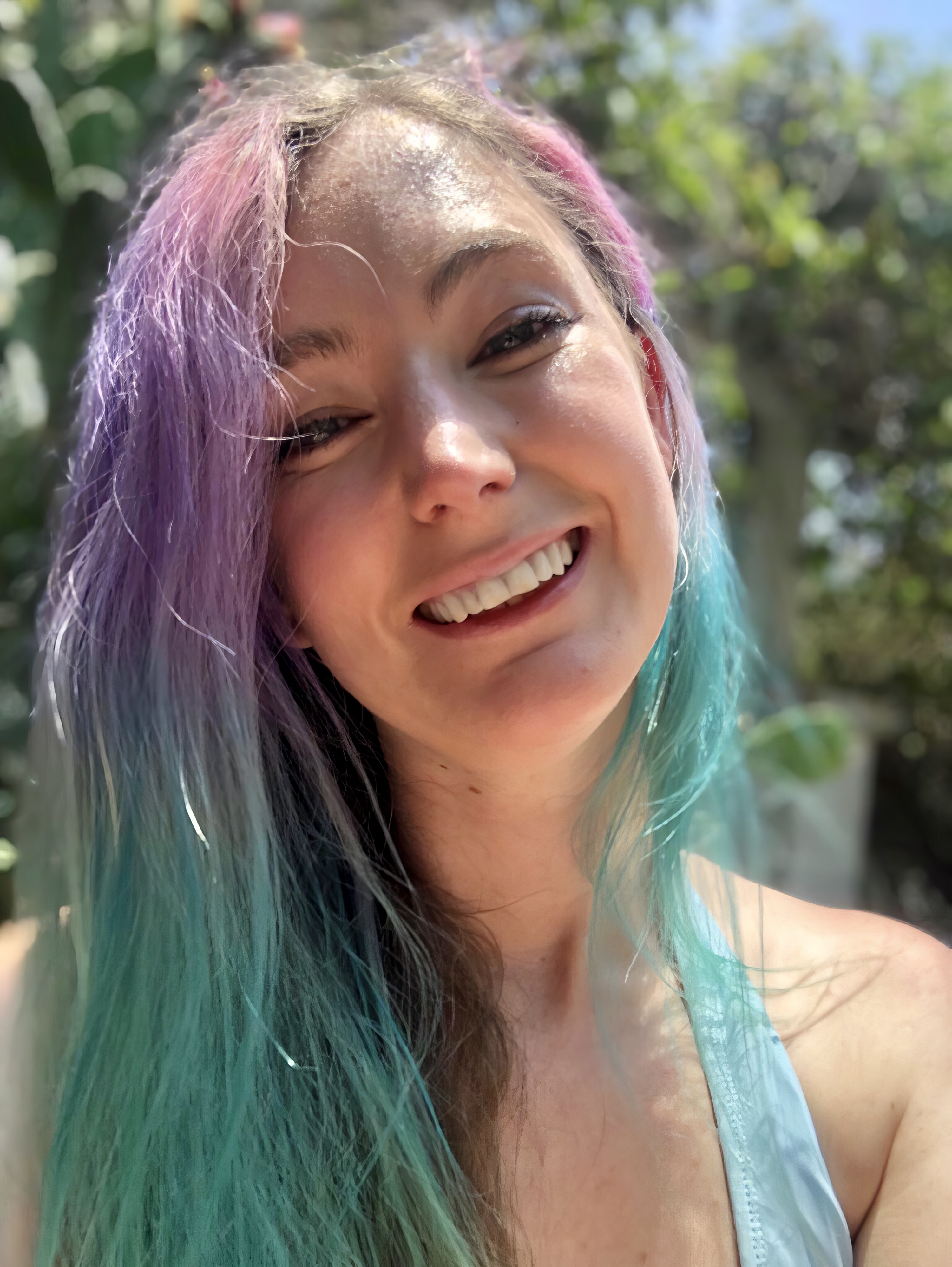 a woman with long hair and a blue tank top smiles at the camera