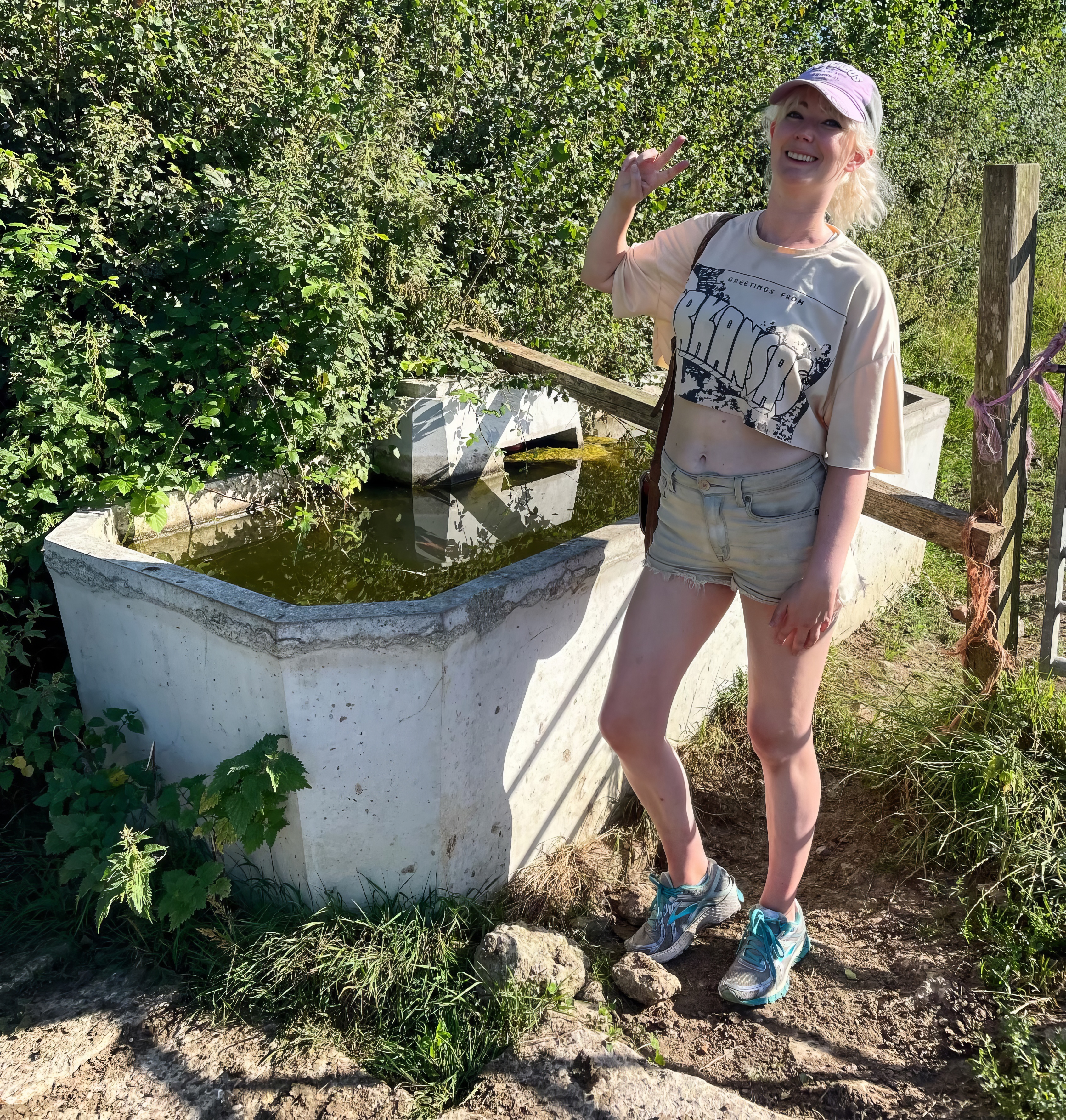 a woman standing next to a small pond